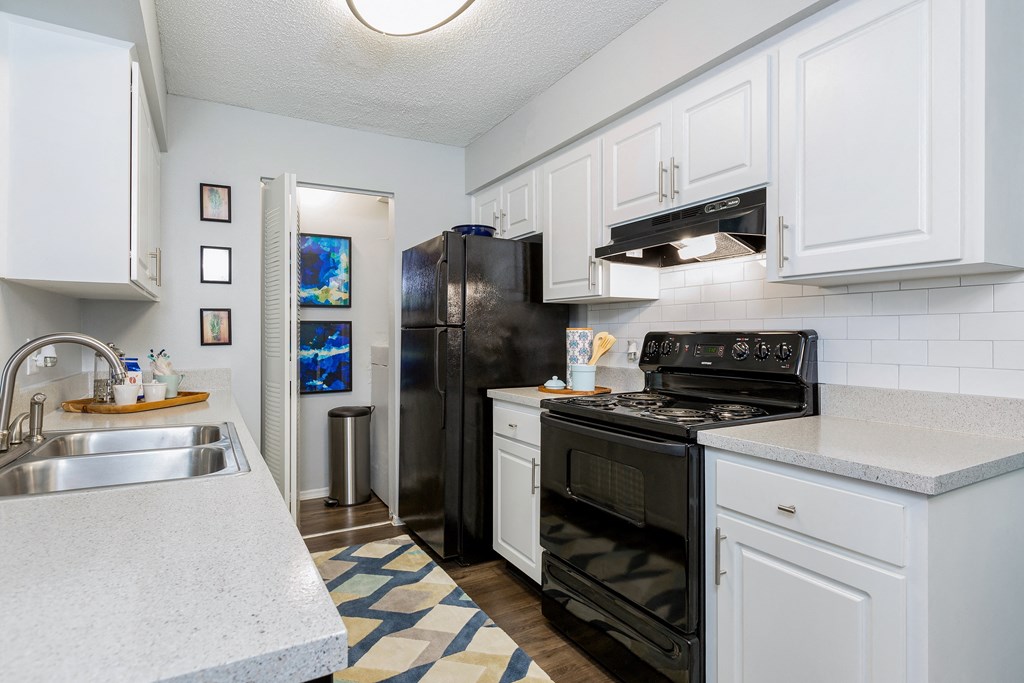 a kitchen with white cabinets and black appliances and a sink