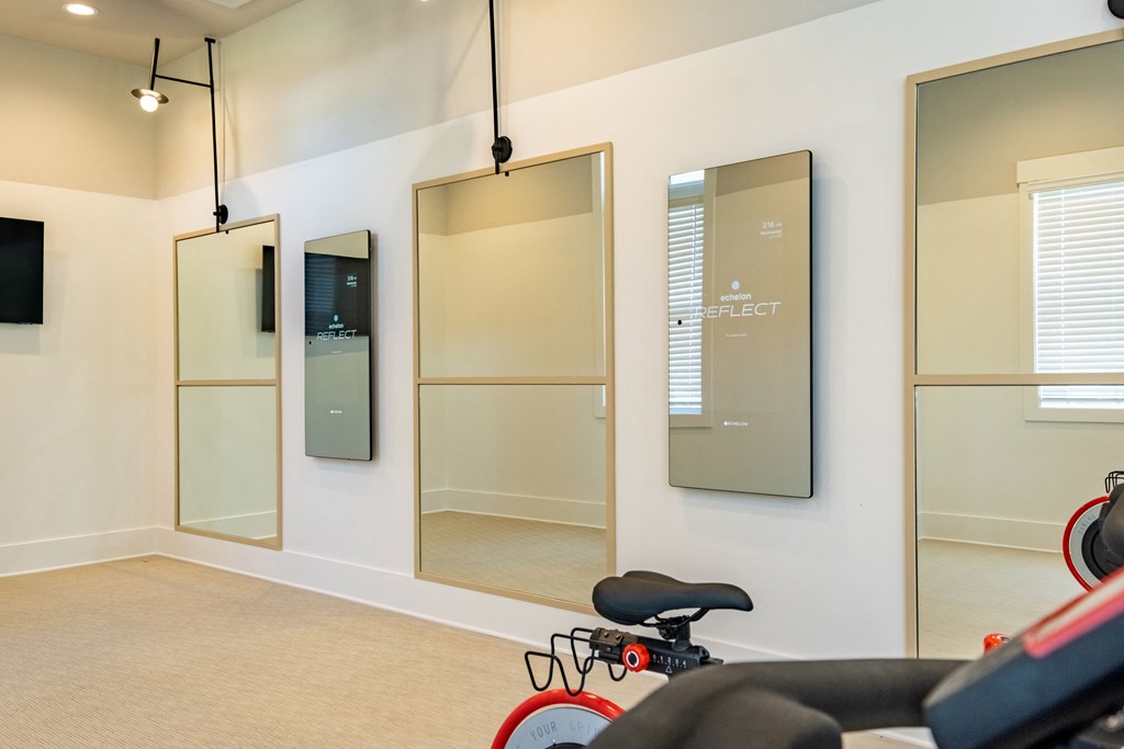 a fitness room with a red exercise bike and mirrors
