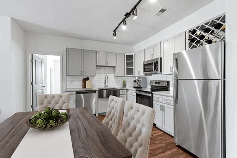 A modern kitchen with a wooden table and white chairs.