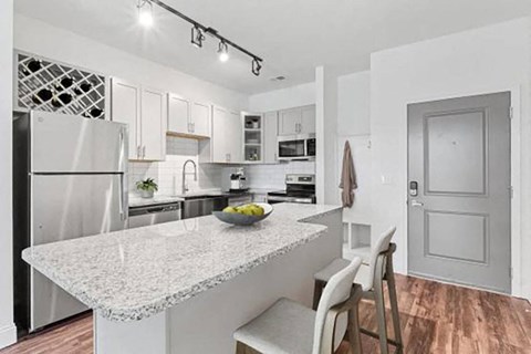 A kitchen with a marble countertop and white cabinets.