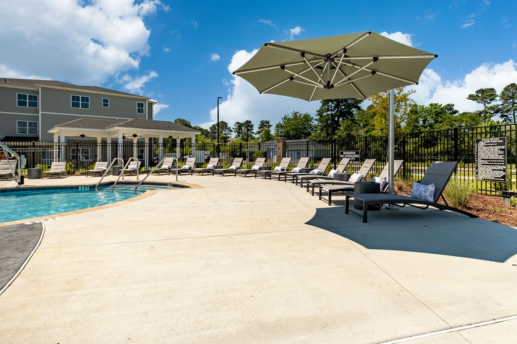 our resort style pool is filled with lounge chairs and an umbrella