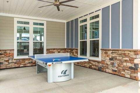 an outdoor ping pong table on the porch of a house