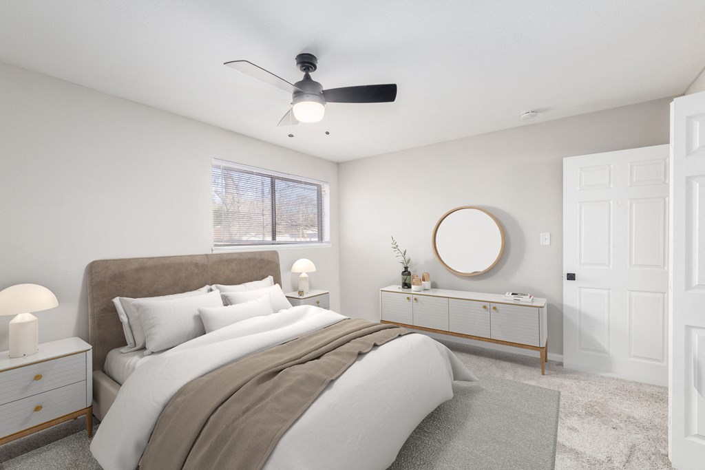 a white bedroom with a large bed and a ceiling fan