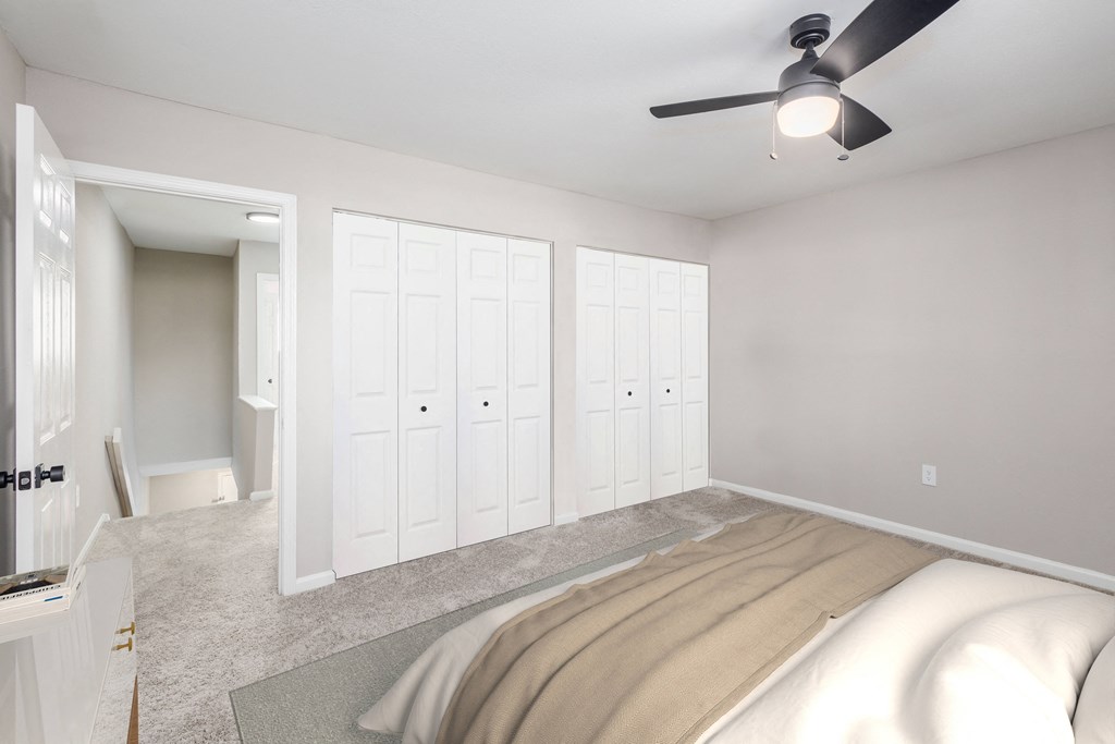 an empty bedroom with a bed and a ceiling fan