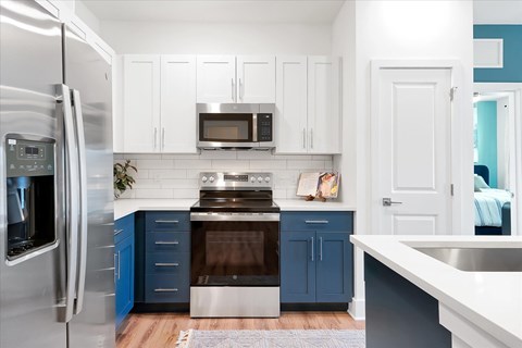 A kitchen with white cabinets and a blue island.