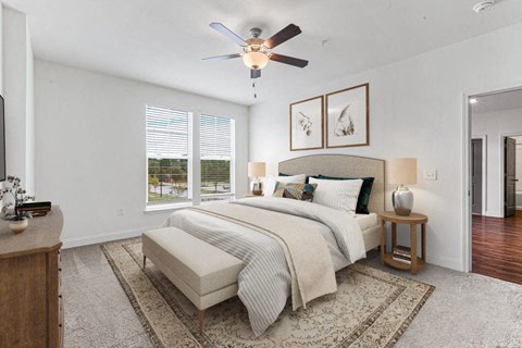 A bedroom with a large bed, a ceiling fan, and a rug on the floor.