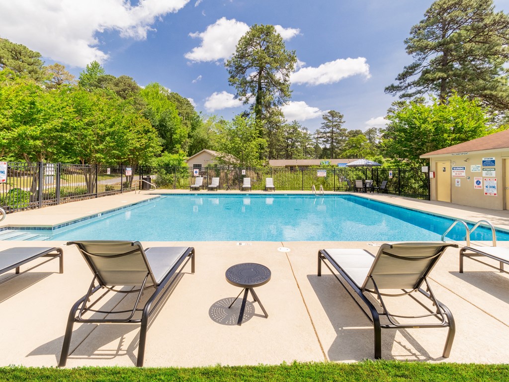 a swimming pool with two chairs and a table next to it