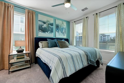 A bedroom with a bed, a ceiling fan, and a window with curtains.