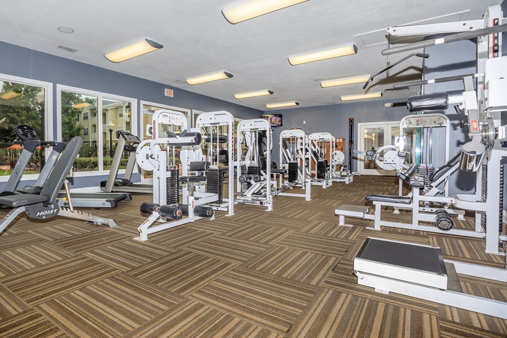 a gym with cardio machines and weights on a wooden floor