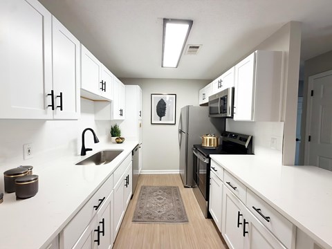 A kitchen with white cabinets and a black fridge.