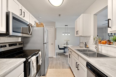an open kitchen with stainless steel appliances and white cabinets