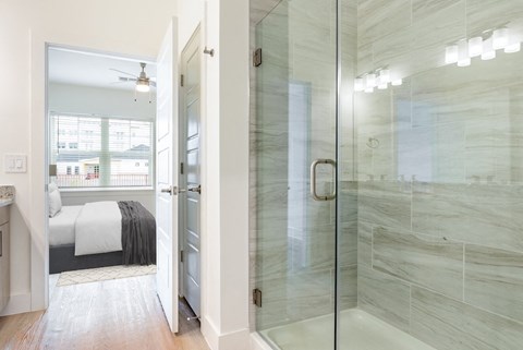 a bathroom with a glass shower and a bed