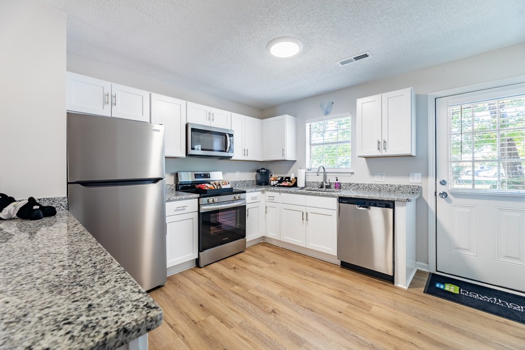 A kitchen with white cabinets and a granite counter top.