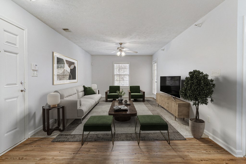 A living room with a grey couch, a green chair, a brown coffee table, and a potted plant.
