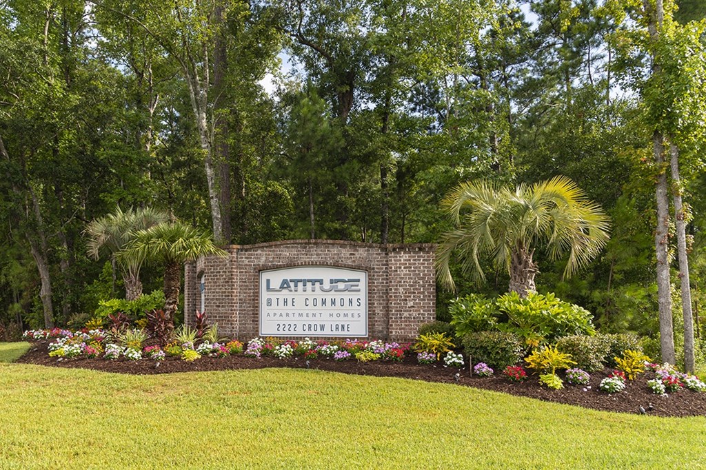 the sign is in front of some flowers and palm trees