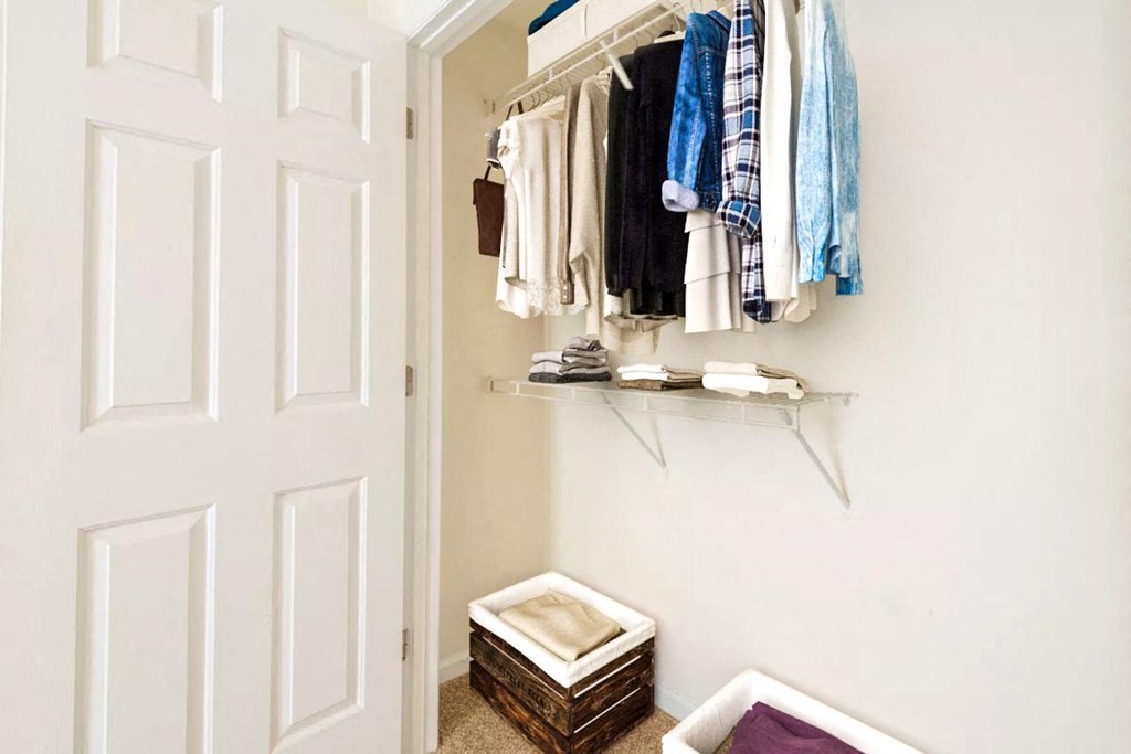a closet with clothes hanging on a rack and a door