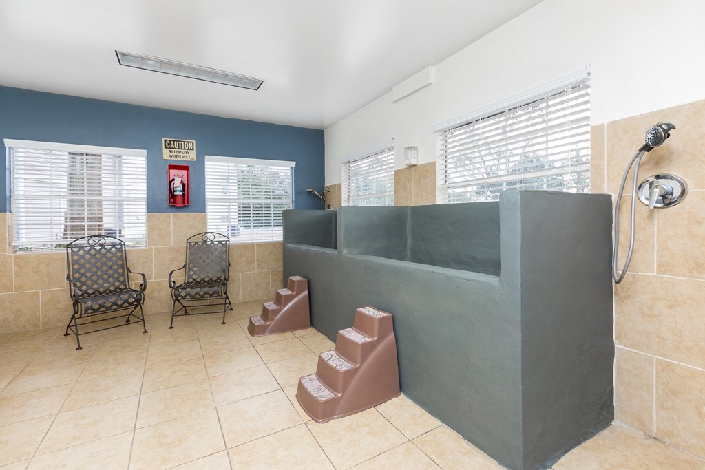 a bathroom with a shower and a sink and two chairs