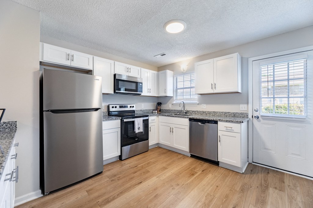 A kitchen with a refrigerator, microwave, oven, and sink.