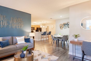a living and dining room area with a couch table and chairs and a kitchen in the background - Photo Gallery 34