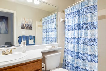 a bathroom with a white toilet and a blue and white shower curtain - Photo Gallery 43