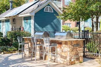 a large outdoor kitchen with a bar and stools in front of a blue house - Photo Gallery 23