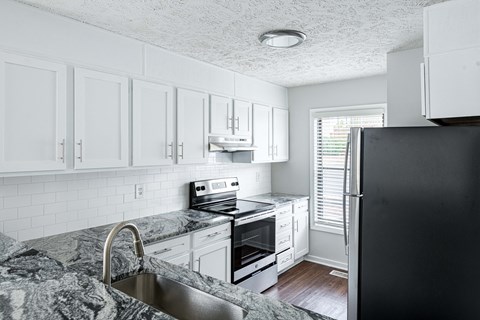 a kitchen with white cabinets and black appliances and a granite counter top