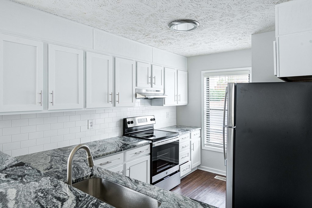 a kitchen with white cabinets and black appliances and a granite counter top