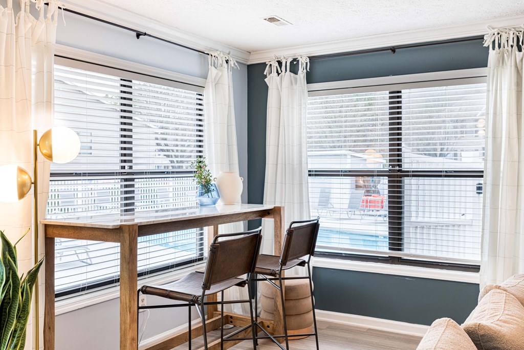 a dining room with two windows and a table with three chairs