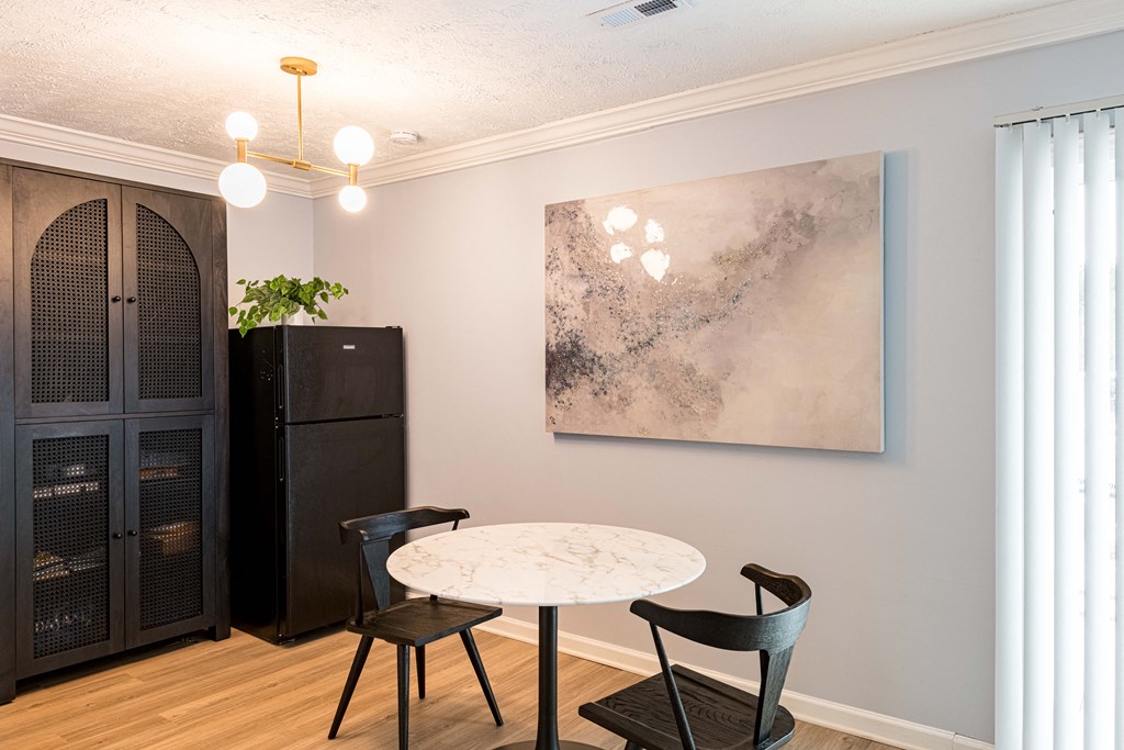 a dining room with a table and chairs and a painting on the wall