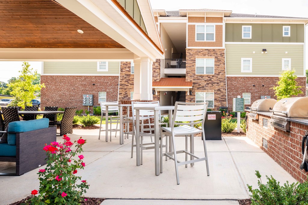 a patio with tables and chairs and a grill