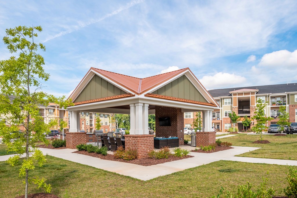 a clubhouse with a brick pavilion with a lawn and trees