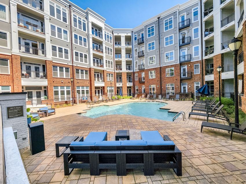 an apartment complex with a pool and lounge chairs - Photo Gallery