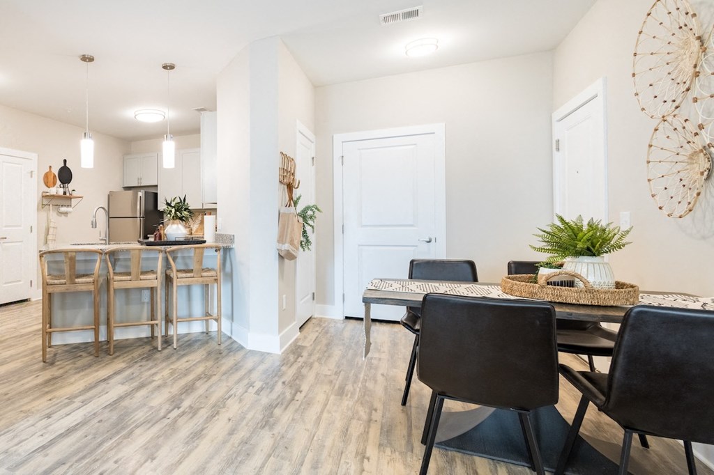 a dining area with a table and chairs and a kitchen in the background