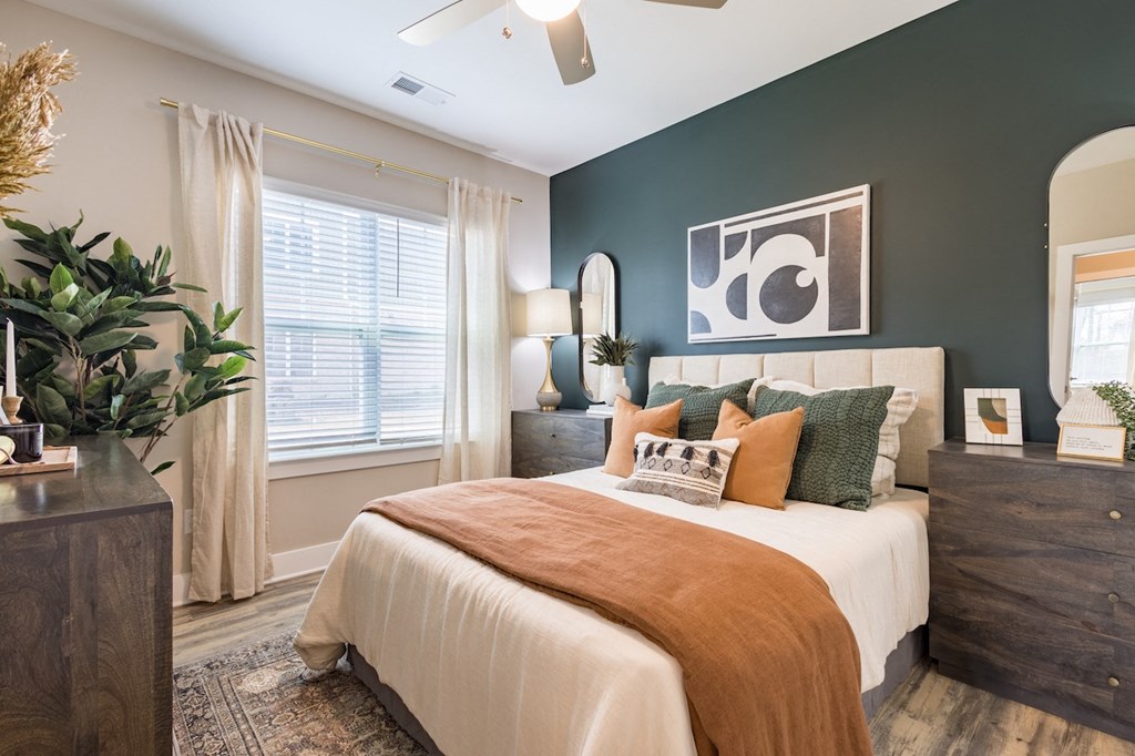 a bedroom with a large window and a ceiling fan