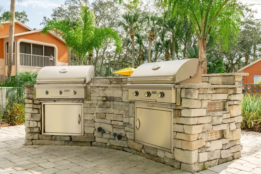 an outdoor kitchen with two grills and two stoves