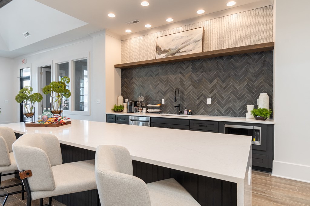 a kitchen with a large white counter top and chairs