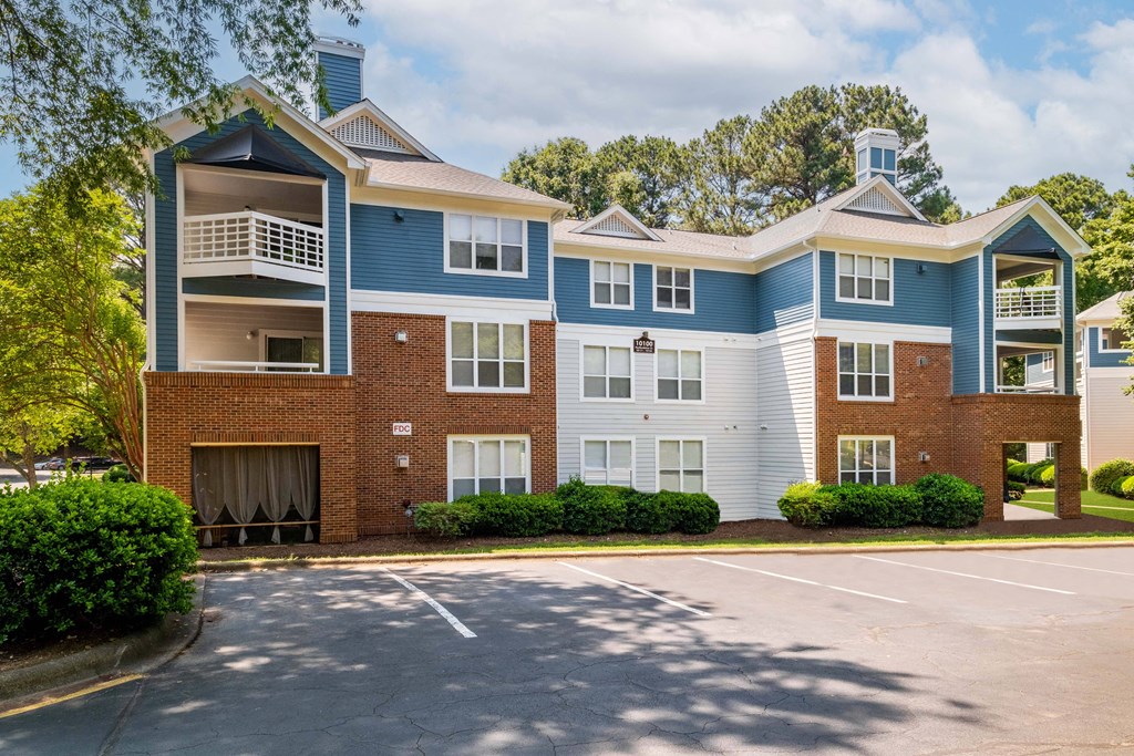 a blue and brick apartment building with a parking lot