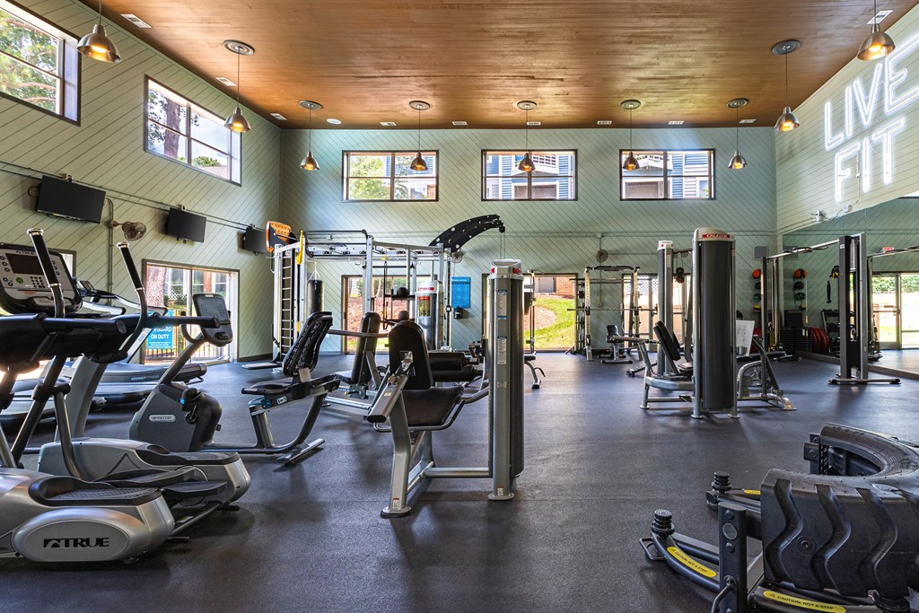 a gym with cardio equipment and weights on the floor and windows