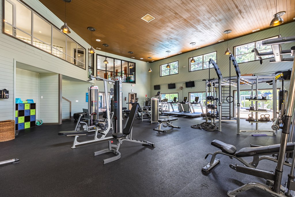 a gym with weights and cardio equipment and windows