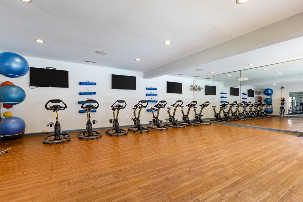 a fitness room with cardio exercise equipment and mirrors on the wall