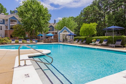 Amenities a swimming pool with chairs and umbrellas in front of apartment buildings