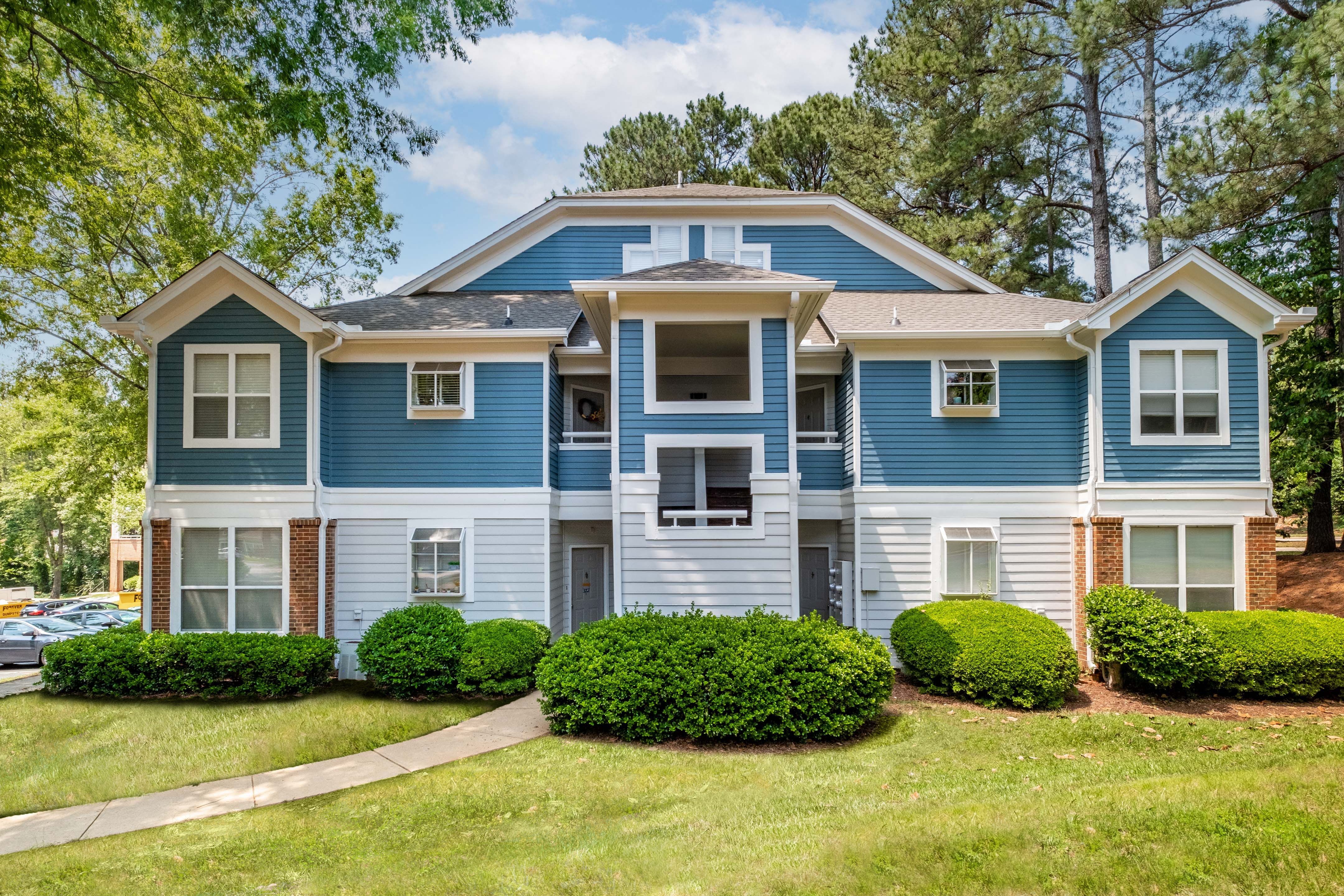 a blue and white apartment building with a green yard in front of it