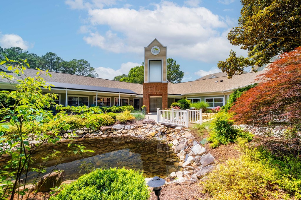 a building with a clock tower and a pond in front of it