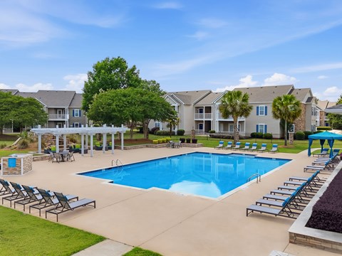 A large swimming pool surrounded by lounge chairs and umbrellas.