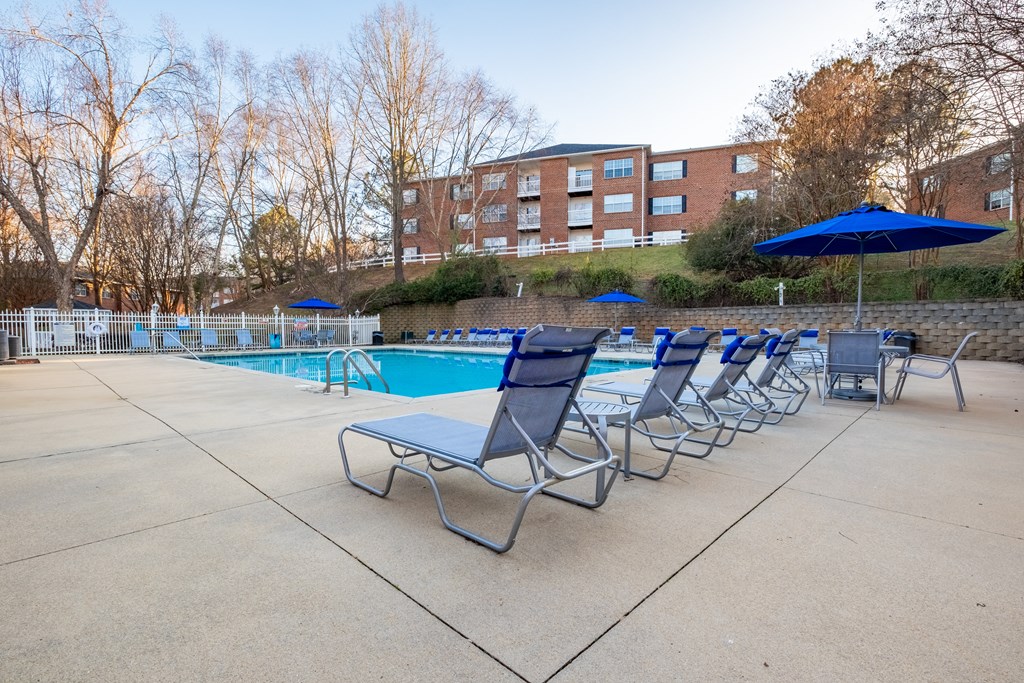 a pool with chairs and umbrellas and a building in the background