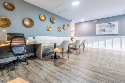 A common area  with blue walls and a desk with chairs and a computer at Amelia Village apartments in Clayton, NC.