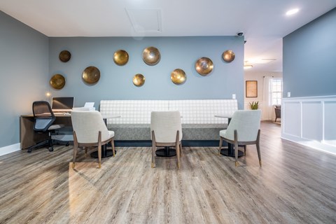 A conference room with white chairs and a blue wall with gold accents at Amelia Village apartments in Clayton, NC.