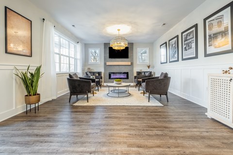 A  room with couches and chairs and a fireplace  in the clubhouse at Amelia Village apartments in Clayton, NC.
