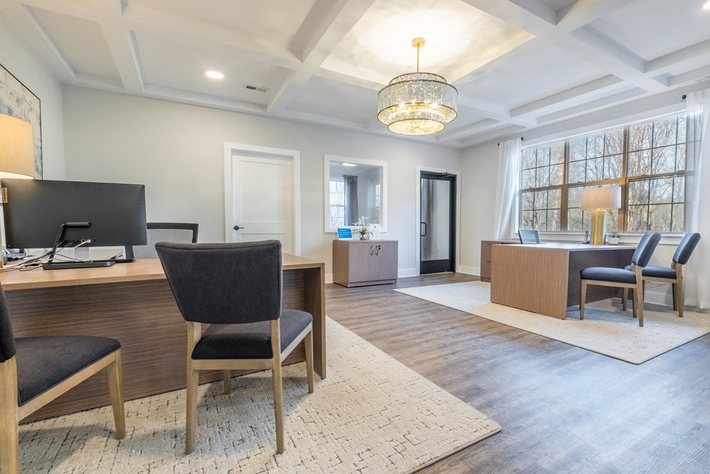 an office with a desk and chairs and a large window