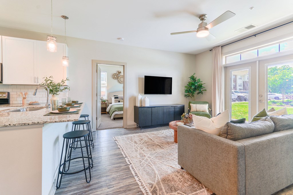 a living room with a couch and a kitchen with a bar and a tv